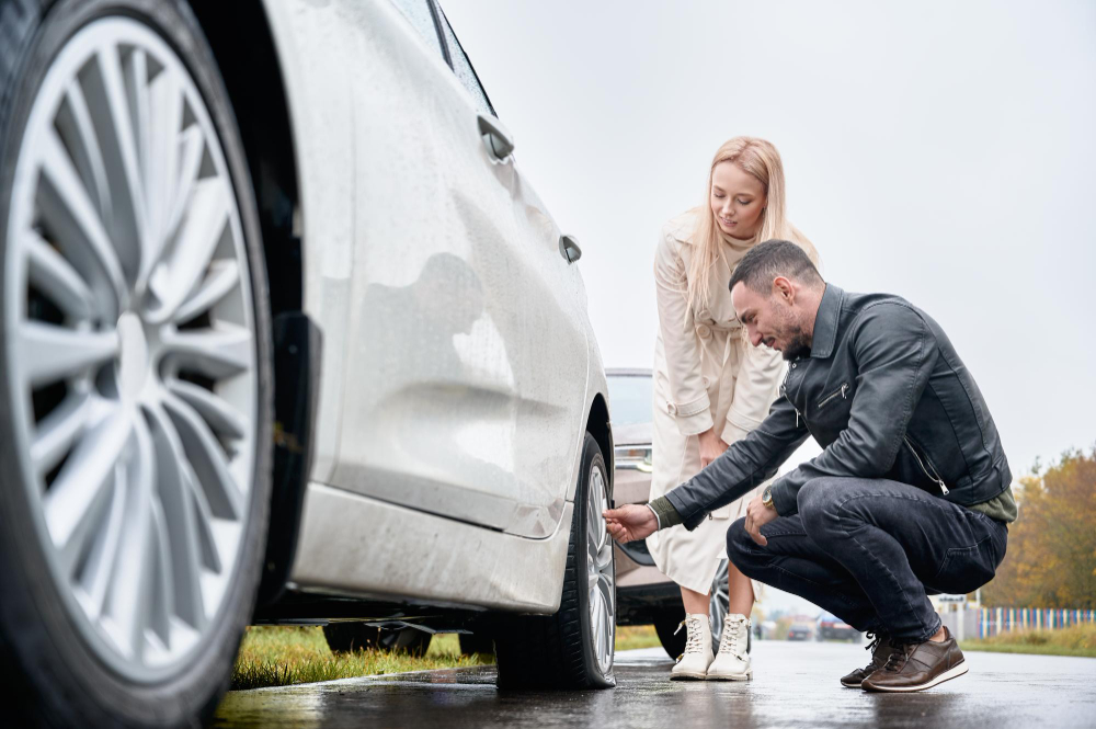 Como fazer a manutenção preventiva de carro novo? 3 jovem ajudando mulher encantadora a consertar a roda do carro